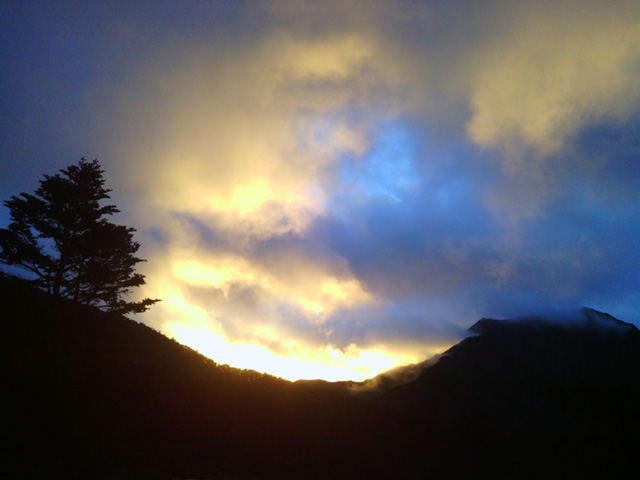 小屋周辺から撮影された雲間に眩しく燃える暁光