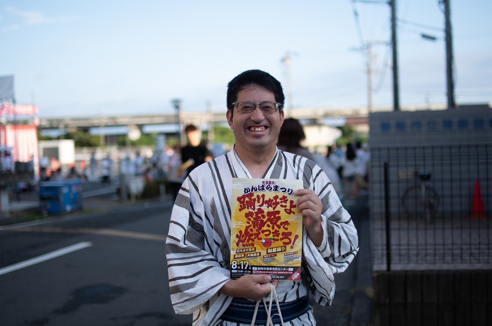 かんばらまつりのチラシを持って笑っている人
