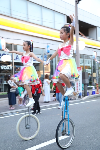 背の高い一輪車に乗ってパレードをする女の子二人