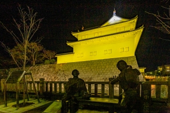 黄色くライトアップされた巽櫓と弥次さん喜多さんの像