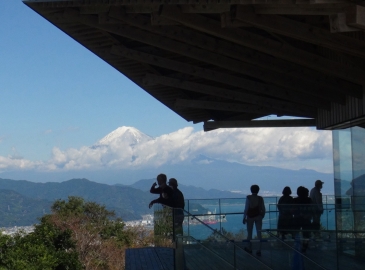 日本平夢テラスのデッキから、雪化粧した富士山を眺める人々。