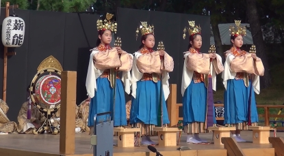 衣装を着た4人の少女が舞台上で演じている。