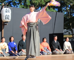 扇子を手に袴姿で演目を演じる女性。