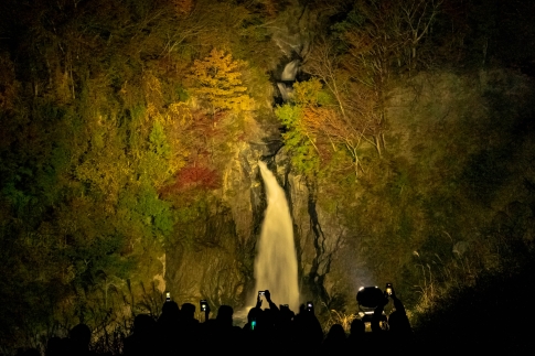 ライトアップされた赤水の滝とそれらを撮影する人々