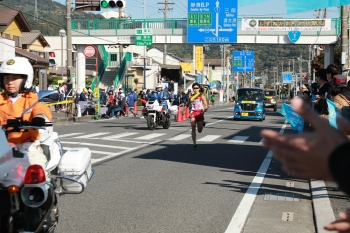 タスキをかけ、国道1号を走る赤いユニフォームの選手
