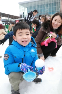 雪のアイスを作って遊ぶ笑顔の男の子とそのお母さん
